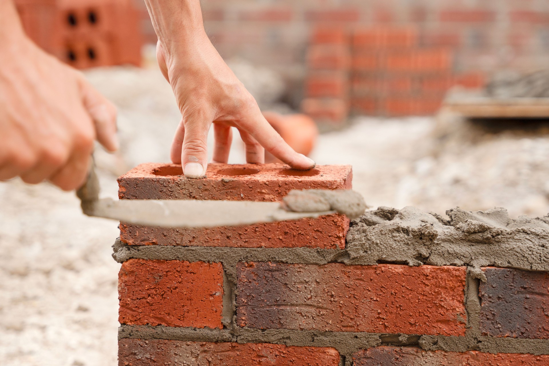 Skilled worker laying bricks in a construction site during daylight, demonstrating craftsmanship in masonry techniques