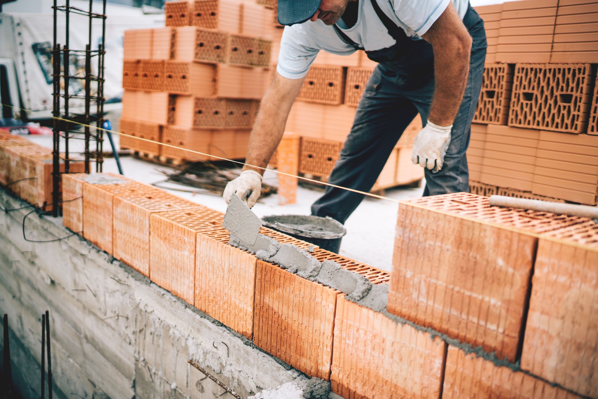 Bricklayer industrial worker installing brick masonry on exterior wall with trowel putty knife