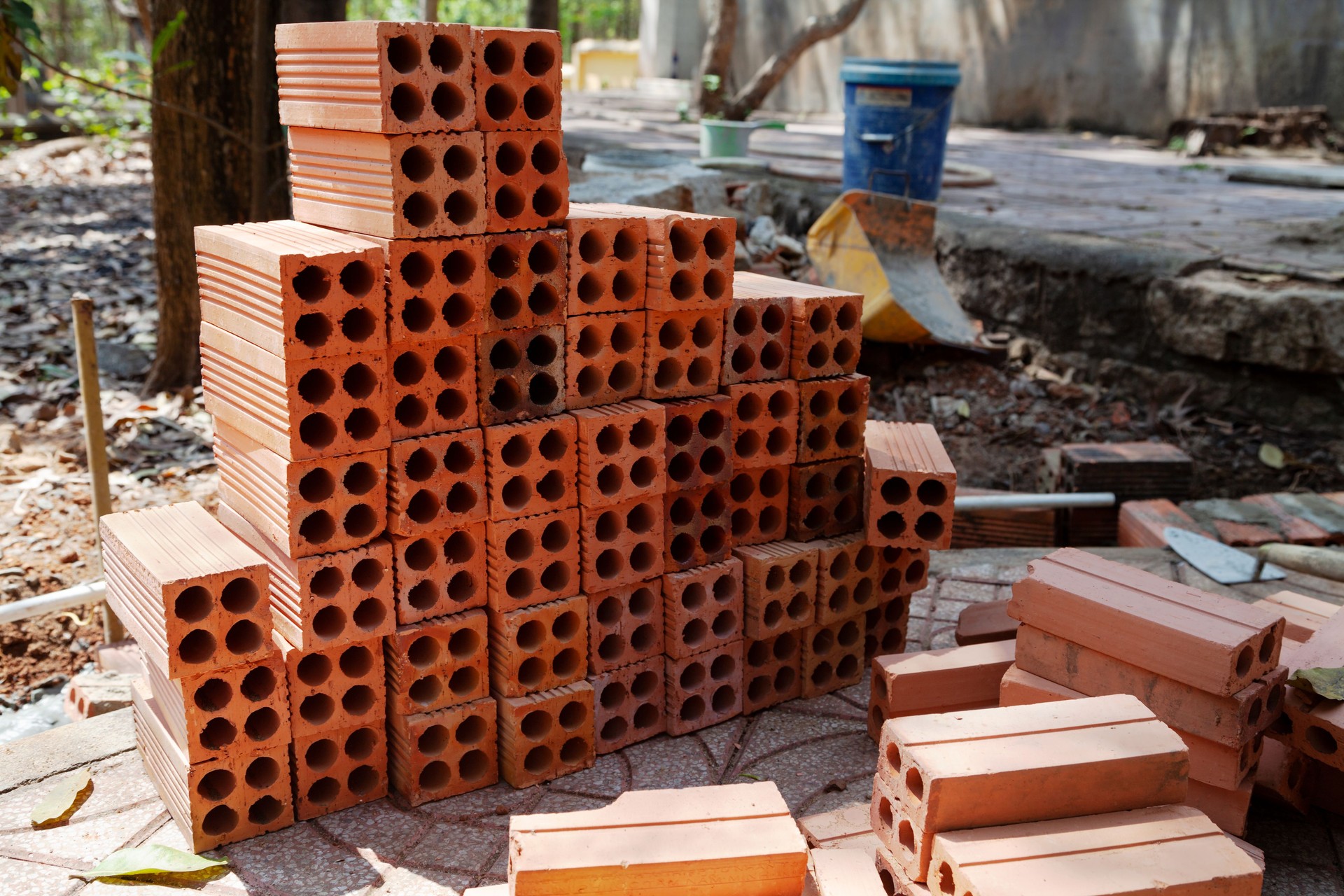 Stack of orange hollow bricks along with brick laying tools at a construction site